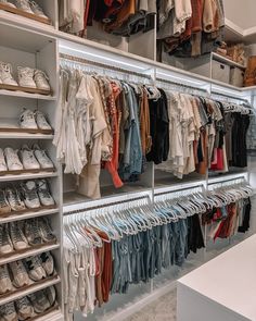 an organized closet filled with shoes and clothing hanging on shelves next to a counter top