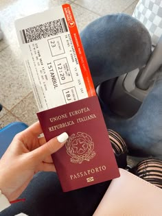 a person holding up a red passport and boarding pass in front of their seat belt