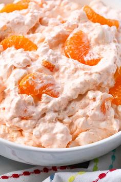 a white bowl filled with fruit salad on top of a colorful table cloth next to an orange slice