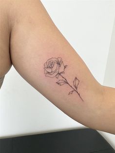 a small rose tattoo on the arm