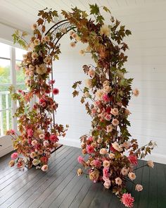 an arch made out of flowers on a wooden floor