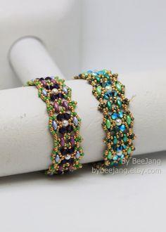 two bracelets are sitting on top of a white piece of paper and one is beaded with multicolored beads