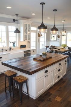 a large kitchen island with stools next to it and lights hanging from the ceiling