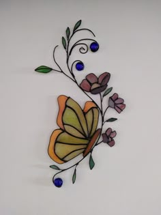 a decorative glass piece with flowers and leaves on it's side, in the shape of a butterfly