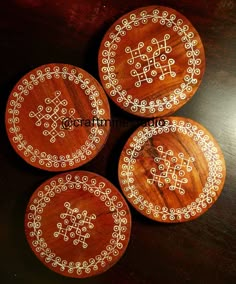 four wooden coasters sitting on top of a table next to each other with white designs