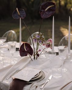 the table is set with place settings and flowers