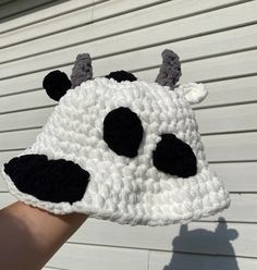 a hand is holding up a crocheted cow hat