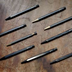 several different types of pens and knives on top of a wooden table with marbled surface