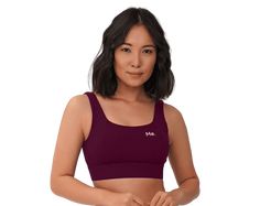 a woman wearing a purple sports bra with her hands on her hips and looking at the camera