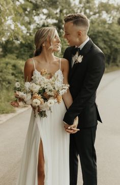 a bride and groom are standing on the road