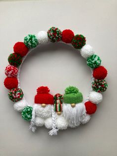 a christmas wreath made with pom - poms and knitted balls is displayed on a white surface