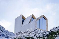 a building on top of a mountain with rocks and grass around it's sides