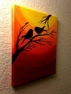 two birds sitting on a tree branch in front of an orange and yellow sunset painting