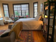 a bed sitting next to a window in a bedroom on top of a wooden floor