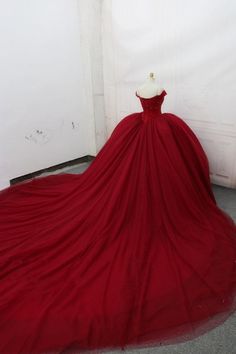 a red ball gown on display in front of a white wall