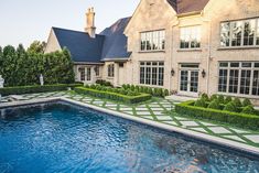 a large house with a pool in front of it and landscaping around the pool area