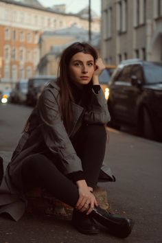 a woman sitting on the ground with her foot up to her face and wearing black shoes