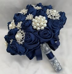 a bridal bouquet with blue roses, pearls and brooches sits on a white background