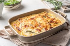 a casserole dish with cheese and herbs in it on a napkin next to other dishes