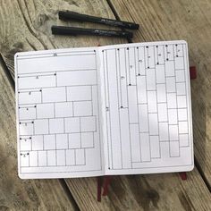 an open planner with two pens on top of it next to a pair of scissors