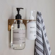 a soap dispenser hanging on a wall next to a bottle of liquid