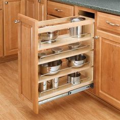 an open cabinet in the middle of a kitchen with pots and pans on it