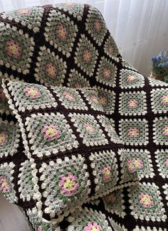 a crocheted blanket sitting on top of a wooden floor next to a window