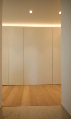 an empty room with white walls and wooden floors is lit by recessed lighting on the ceiling