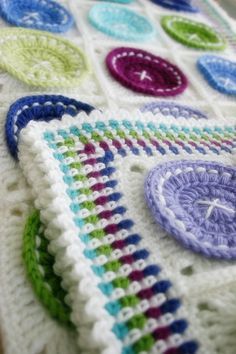 a crocheted blanket with multicolored circles on it's edge and a button at the center