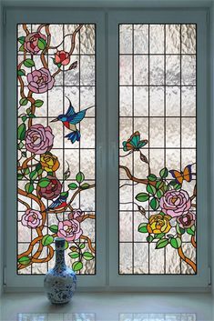 a vase sitting in front of two stained glass windows with birds and flowers on them