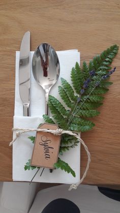 a fork and spoon sitting on top of a white napkin next to a green plant