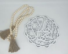 a tasseled wooden bead necklace with an arabic calligraphy in the center