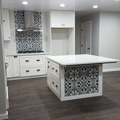 an empty kitchen with white cabinets and black tile backsplashes on the walls