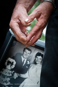 a man and woman holding hands in front of a picture frame with their wedding pictures on it