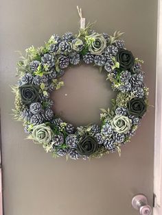 a wreath made out of succulents hangs on the door