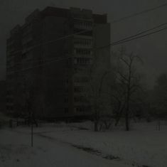 an apartment building on a snowy day with power lines in the foreground and snow covered ground