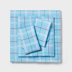 the blue plaid sheets are folded on top of each other