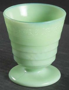 a green glass cup sitting on top of a table