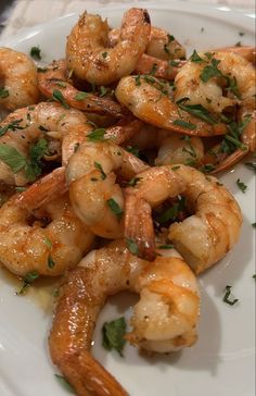 a white plate topped with cooked shrimp and garnished with parsley