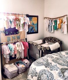 a baby's room with clothes hanging on the wall and a bed in the corner