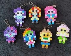 six perler bead keychains in different colors and sizes on a black surface