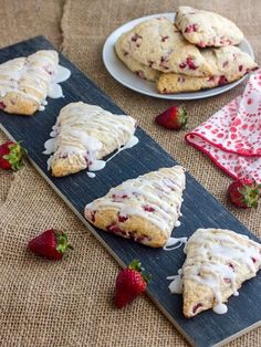 strawberry scones with icing and strawberries on a table