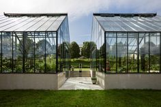 two glass greenhouses sitting on top of a lush green field