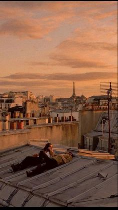 two people laying on the roof of a building in paris, france at sunset or dawn