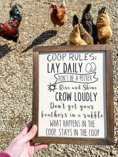 a hand holding up a sign that says coop rules and roosters in the coop