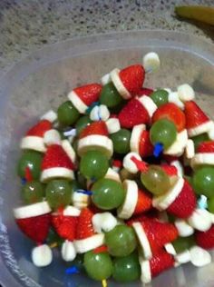 a bowl filled with green and red fruit covered in santa claus's hat candy