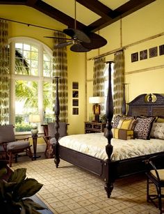 an image of a bedroom with yellow and green colors on the walls, ceiling fan and bed