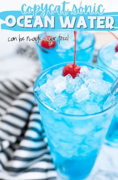 two glasses filled with blue liquid and ice on top of a black and white table cloth