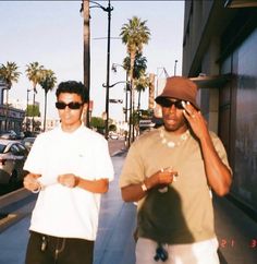 two men walking down the street talking on their cell phones