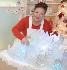 a woman standing in front of a snow - covered cake on top of a table